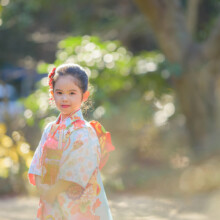 柔らかな木漏れ日に包まれながら振り返る晴れ着姿の女の子。自然光を活かした鎌倉・妙本寺での七五三ポートレート。