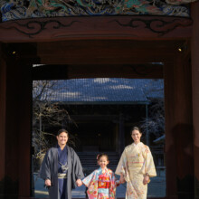 妙本寺の山門前で手をつないで歩く家族。七五三を迎えた女の子を中心に自然な笑顔を残した家族記念撮影。