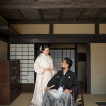 白無垢と黒紋付袴を着た新郎新婦が古民家の和室で微笑み合う結婚写真