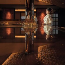落ち着いた照明の和風の部屋で、生花越しに立つ和装の新婦