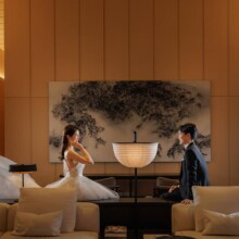 背景に絵が飾られたソファの並ぶ空間で、向かい合って座る洋装の新郎新婦