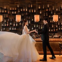 ワインが飾られているバーカウンターの前で踊る洋装の新郎新婦