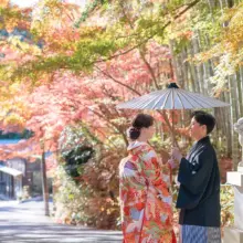 鎌倉・建長寺で秋に撮影した和装前撮り 鎌倉・建長寺で色打掛を着用した新婦と紋付袴を着用した新郎が番傘を持ち向かい合っている和装前撮り