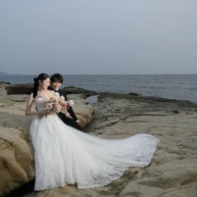 春の海を背景にした稲村ガ崎で。ウエディングドレスとタキシードでブーケを見つめるお二人。