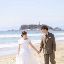 鎌倉・七里ガ浜で春に撮影した洋装前撮り 鎌倉・七里ガ浜でウェディングドレスを着用した新婦と持込のスーツを着用した新郎が手を取って歩く洋装前撮り