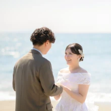 鎌倉・七里ガ浜で春に撮影した洋装前撮り 鎌倉・七里ガ浜でウェディングドレスを着用した新婦と持込のスーツを着用した新郎が手を取り合う洋装前撮り