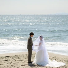 鎌倉・七里ガ浜で春に撮影した洋装前撮り 鎌倉・七里ガ浜でウェディングドレスを着用した新婦と持込のスーツを着用した新郎がベールをかぶって写る洋装前撮り