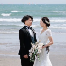 鎌倉・由比ガ浜で春に撮影した洋装前撮り 鎌倉・由比ガ浜でウェディングドレスを着用した新婦とタキシードを着用した新郎が見つめ合って写る洋装前撮り