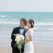 鎌倉・由比ガ浜で春に撮影した洋装前撮り 鎌倉・由比ガ浜でウェディングドレスを着用した新婦とタキシードを着用した新郎が空を見つめる洋装ウェディングフォト