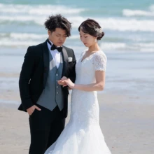 鎌倉・由比ガ浜で春に撮影した洋装前撮り 鎌倉・由比ガ浜でウェディングドレスを着用した新婦とタキシードを着用した新郎が手を取り合う洋装ウェディングフォト