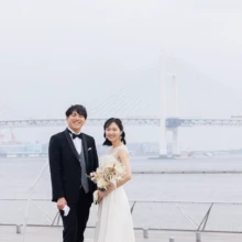 横浜・大桟橋で春に撮影した洋装前撮り 横浜・大桟橋でウェディングドレスを着用した新婦とタキシードを着用した新郎がブーケを持って写る洋装ウェディングフォト