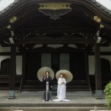 妙本寺の本堂前で、番傘を手に和装フォトウェディングを楽しむおふたり。|縁グラフィの姉妹ブランドLuca 鎌倉・妙本寺の本堂前で番傘を手に白無垢と紋付袴で和装フォトウェディングを行う新郎新婦