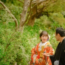 鎌倉 和装 N様・M様 2021.03.22 海蔵寺の白い雪柳を背景に、オレンジの色打掛姿の新婦と黒紋付袴姿の新郎が手をつないで見つめ合う
