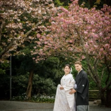 鎌倉 和装 S様・S様 2021.04.02 妙本寺で淡いピンクの桜を背景に、白無垢の新婦と黒紋付袴の新郎が寄り添って立つ春の鎌倉前撮り