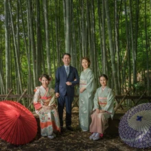 成人式撮影 H様 2021.05.09 檑亭の竹林で赤と紫の和傘を添え、振袖姿の姉妹と着物姿の母親、スーツ姿の父親が並ぶ成人式家族撮影