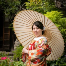 鎌倉 和装 I様・S様 2021.05.28 瑞泉寺の新緑と赤い花に囲まれ、白い和傘を差した色打掛姿の新婦が微笑む鎌倉前撮りのソロカット