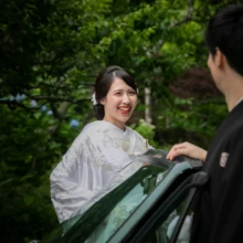 鎌倉 和装 I様・S様 2021.05.28 緑に囲まれたオープンカーのそばで、白無垢姿の新婦が黒紋付袴の新郎を見て笑う鎌倉フォトウェディング