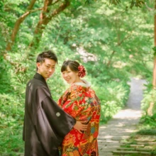鎌倉 和装 M様・K様 2021.05.30 瑞泉寺の緑豊かな小径で、赤い色打掛の新婦を黒紋付袴の新郎が抱き寄せ、二人で笑顔を見せる和装前撮り