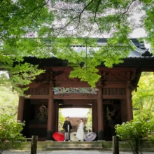鎌倉 和装 O様・M様 2021.05.31 新緑に包まれた妙本寺の門と境内を広く背景に、白無垢の新婦と黒紋付袴の新郎が並ぶ鎌倉前撮り