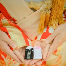 鎌倉 和装 M様・Y様 2021.06.01 金色の房飾りがある色打掛の膝上で、新郎新婦が黒と白の小箱に手を添える持込みアイテムのカット