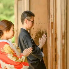 鎌倉 和装 M様・Y様 2021.06.01 建長寺の木戸に向かって手を合わせる黒紋付袴の新郎と、その後ろに寄り添う朱赤の色打掛の新婦