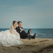 鎌倉 和洋装 H様・S様 2021.06.15 稲村ヶ崎の岩場に座り、ウェディングドレスとタキシード姿で愛犬と海を眺める新郎新婦の洋装前撮り