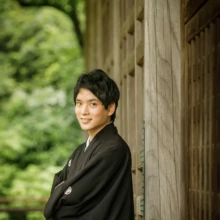 鎌倉 和装 T様・T様 2021.06.21 新緑を望む妙本寺の木造廊下で、腕を組んで柱にもたれながら微笑む黒紋付袴姿の新郎