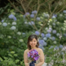 鎌倉 和装洋装 S様・S様 2021.06.25 紫陽花が咲く庭で、紫のブーケを持ち純白のウェディングドレス姿で微笑む新婦の鎌倉フォトウェディング