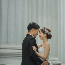 東京 洋装 T様・K様 2021.06.30 日本橋の大きな円柱を背景に、タキシードの新郎と花飾りを着けたウェディングドレス姿の新婦が額を寄せ合う東京前撮り
