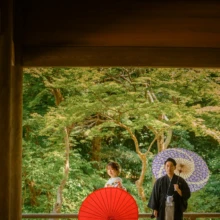 鎌倉 和装 S様・N様 2021.07.12 妙本寺の回廊を額縁のように取り入れ、赤と紫の和傘の間に立つ色打掛の新婦と黒紋付袴の新郎の鎌倉前撮り