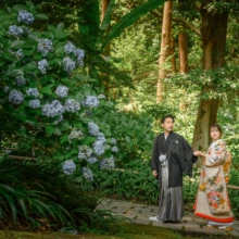 鎌倉 和装 S様・N様 2021.07.12 妙本寺の参道で、淡い色打掛姿の新婦と黒紋付袴の新郎が青紫の紫陽花のそばに並ぶ夏の鎌倉前撮り