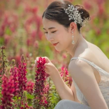 北海道 洋装 M様・K様 2021.07.16 富良野・美瑛のルピナス畑で、刺繍入りウェディングドレス姿の新婦が花に顔を近づける北海道洋装前撮り