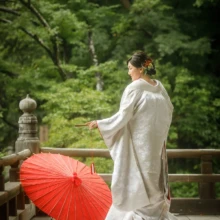 鎌倉 和装 N様・A様 2021.09.09 妙本寺の木橋で、赤い差し色が映える白無垢姿の新婦が朱色の和傘を足元に置き、横向きに立つ鎌倉前撮り