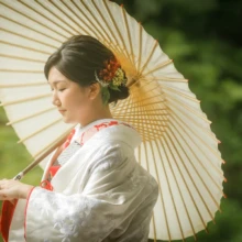 鎌倉 和装 N様・A様 2021.09.09 妙本寺の新緑を背景に、白い和傘を差した白無垢姿の新婦が髪飾りを見せて横を向く鎌倉和装前撮り