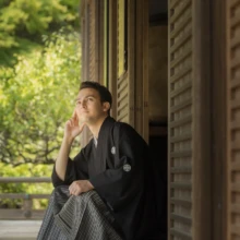 鎌倉 和洋装 K様・M様 2021.09.24 建長寺の回廊に腰掛け、片手を頬に添えて遠くを見つめる黒紋付袴姿の新郎の鎌倉前撮りソロカット