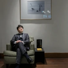 鎌倉 洋装 A様・I様 2020.11.12 額装作品が飾られた洋館の室内で、黒いタキシード姿の新郎が緑色の一人掛け椅子に脚を組んで座る