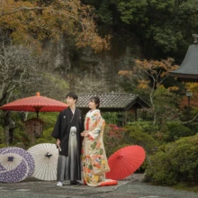 鎌倉 和装 S様・A様 2021.11.21 晩秋の海蔵寺で、複数の和傘と庭園を背景に並ぶ色打掛の新婦と黒紋付袴の新郎の和装前撮り