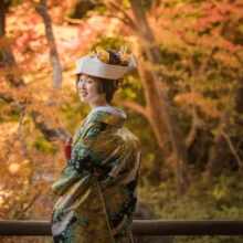 鎌倉 和装 T様・M様 2021.12.20 妙本寺の紅葉を背景に、角隠しと緑を基調とした色打掛をまとい、振り返ってほほ笑む新婦の色打掛前撮り