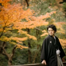 鎌倉 和装 A様・Y様 2021.12.07 晩秋の妙本寺で、紅葉を背景に橋へ立ち、視線を落とす黒紋付袴姿の新郎の鎌倉和装前撮り