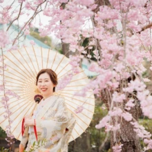 鎌倉 和装 M様・M様 2022.04.01 しだれ桜に囲まれた建長寺で、白い和傘を差して笑顔を見せる淡い色打掛姿の新婦のソロカット