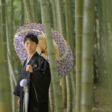 鎌倉横浜 和洋装 S様M様 2022.04.10 建長寺の竹林で、紫色の柄入り和傘を肩に差し、正面を見つめる黒紋付袴姿の新郎のソロカット