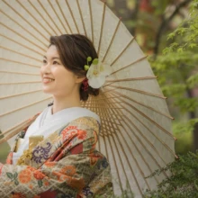 横浜 和洋装 Y様・O様 2022.04.18 新緑に囲まれた日本大通りで、白い和傘を肩に色打掛をまとい、笑顔を見せる花嫁の横浜和装前撮り