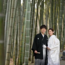 鎌倉 和装 K様・E様 2025.02.16 鎌倉の竹林で、白無垢の新婦と黒紋付袴の新郎が肩を寄せ、正面を向いてほほ笑む全身構図