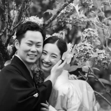 鎌倉 和装 O様・S様2026.06.26 紫陽花の枝を背景に、黒紋付の新郎と白無垢の花嫁が頬を寄せて笑う、鎌倉和装前撮りのモノクロポートレート