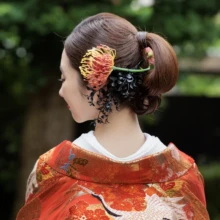 鎌倉 和装 O様・S様2026.06.26 緑を背景に、鶴文様の赤い色打掛をまとった花嫁の後ろ姿と、まとめ髪に添えた赤金の髪飾りを捉えた鎌倉和装前撮り