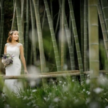 鎌倉 和洋装 H様・A様 2021.03.29 英勝寺の竹林と白い小花を前景に、ブーケを持つウェディングドレス姿の新婦が立つ春の洋装前撮り
