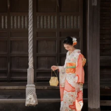 成人式撮影 M様 2023.08.09 しめ縄の掛かる鎌倉の社殿前で、金色の和装バッグを手に視線を落とす、淡い桃色の振袖姿の女性