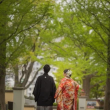 横浜 和装 Y様・O様 2022.04.14 山手イタリア山庭園の新緑に包まれた並木道で、黒紋付の新郎と赤い色打掛の新婦が並ぶ横浜和装前撮り