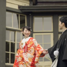 横浜 和装 Y様・O様 2022.04.14 山手西洋館の窓を背景に、手をつないで見つめ合う黒紋付の新郎と華やかな色打掛姿の新婦