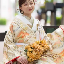 馬車道の街並みで、華やかな色打掛とブーケを美しく残した花嫁の和装ウェディングフォト|縁グラフィの姉妹ブランドLuca 横浜・馬車道で華やかな色打掛をまとい、オレンジのブーケを手に微笑む花嫁